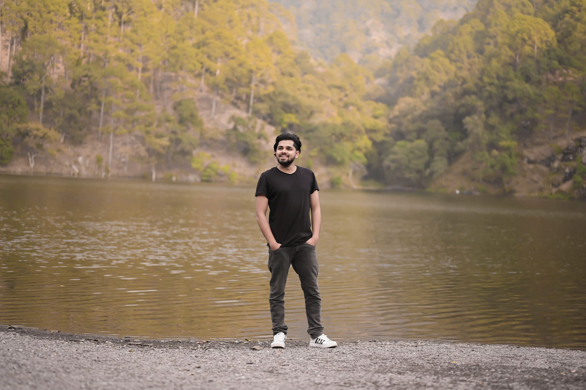 Piyush Dixit standing by a lake in the hills, in a black t-shirt